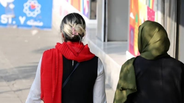 An Iranian woman (l) without a mandatory headscarf, or hijab, walks in a street in Tehran, Iran next to a woman wearing a headscarf on 15 September