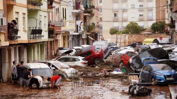 Residents look at cars piled up after being swept away by floods in Valencia, Spain, Wednesday, Oct. 30, 2024