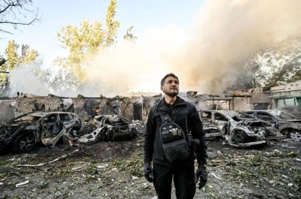 A man is pictured against the background of cars destroyed as a result of Russian shelling.