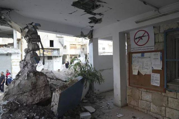 Palestinians pass by the rubble of the UNRWA office that was partly demolished during an Israeli army operation in the West Bank, 31 October, 2024