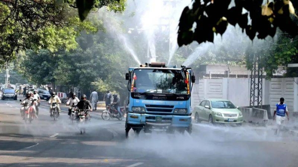 Pakistani municipal corporation workers spray water on roads to control the smog situation