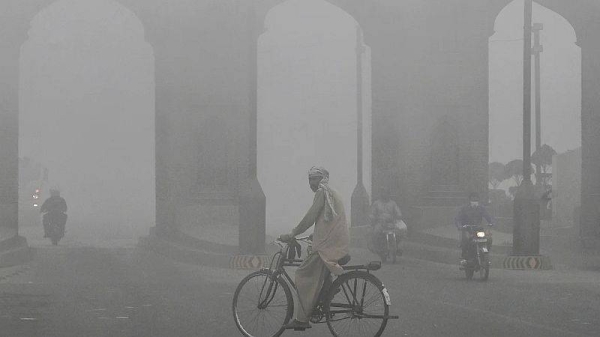 A cyclist rides along a street engulfed in thick smog, in Lahore on November 10, 2024