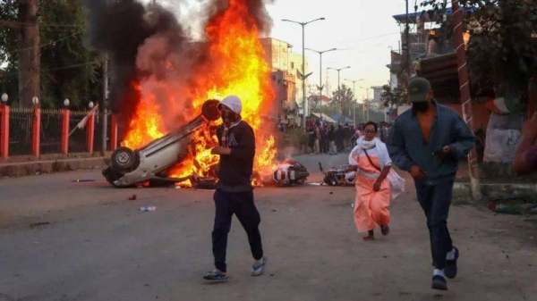 Protesters run past a burning vehicle in Imphal on Saturday