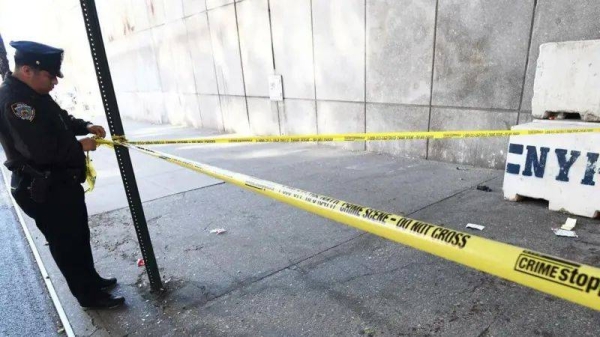 New York Police Department Police officer ties yellow caution tape around crime scene that includes bloodied side walk