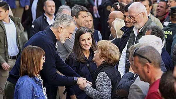 Spain's King Felipe VI speaks with a woman next to Spain's Queen Letizia, as they visit the area devastated by last month's flooding in Chiva, near Valencia, Spain