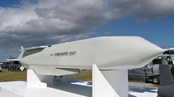 A Storm Shadow cruise missile, which is several meters long and has a white glossy outer layer, pictured on a display stand at an air show in Farnborough.