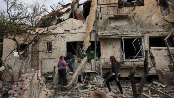 People check through rubble near a damaged house in Israel after rocket strike