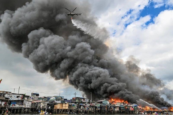 A Philippine Air Force helicopter drops water over shanty settlements ablaze in Tondo, Manila