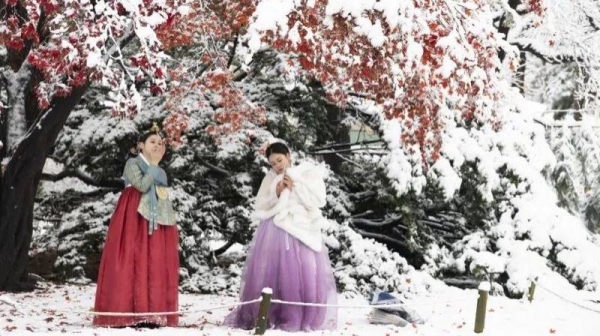 Macao tourists wearing Korean traditional Hanbok dresses take pictures amid snowfall at the Gyeongbokgung Palace in Seoul, South Korea, 27 November 2024