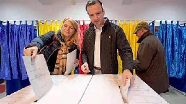 A man and a woman post their votes in Romania's parliamentary elections, in Bucharest, 1 December 2024