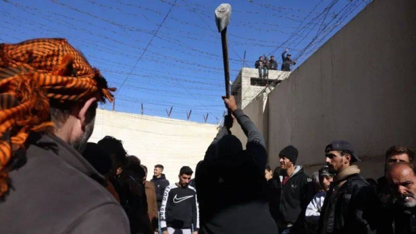 A man uses a sledgehammer during the search for secret cells containing detainees at Saydnaya prison, north of Damascus