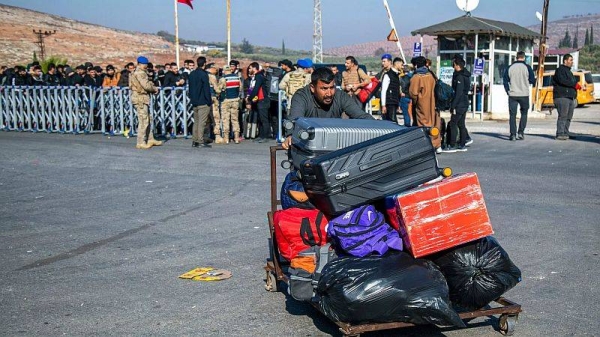 Syrians arrive to cross into Syria from Turkey at the Cilvegozu border gate, near the town of Antakya, southern Turkey, Monday, 9 December 2024