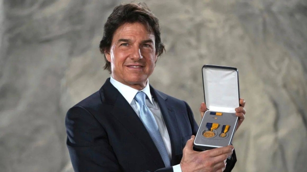 Tom Cruise posing with the Distinguished Public Service Award he received Tuesday from The United States Secretary of the Navy Carlos Del Toro in London