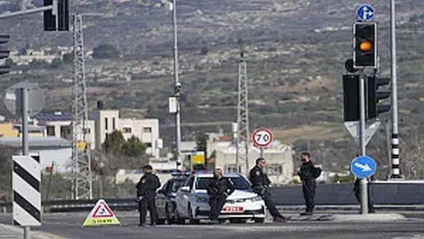 Israeli policemen block a main road after gunmen opened fire on cars and a bus carrying Israelis in the occupied West Bank, killing at least three people