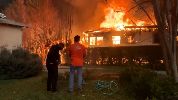 Volunteers try to douse Gail's home and yard to keep the flames at bay