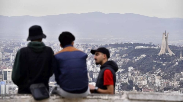 Residents talk, with the monument to the Martyrs in background, right, Monday, Jan. 6, 2025 in Algiers