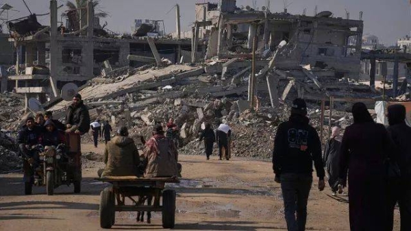 FILE - Palestinians carry UN-donated flour in Khan Younis, central Gaza Strip, on Saturday Dec. 14, 2024