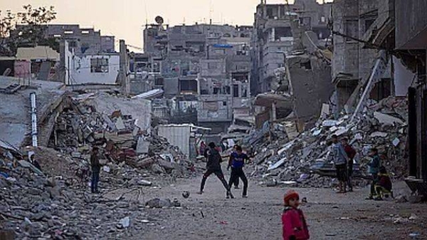 Palestinian children play next to buildings destroyed by Israeli army strikes in Khan Younis, Gaza Strip, Tuesday, Jan. 7, 2025