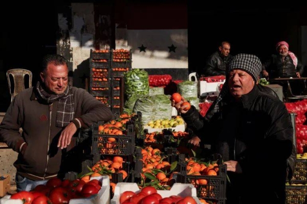 People sell produce at a market in Damascus