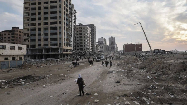 Displaced Palestinians pass destroyed buildings as they return to the north from the southern Gaza Strip on Tuesday