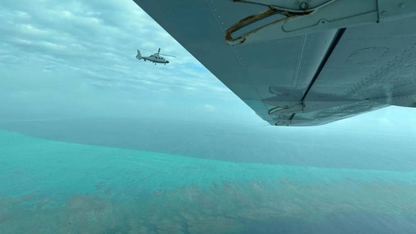 A Chinese military helicopter flies close to a Philippine Bureau of Fisheries and Aquatic aircraft, above Scarborough Shoal in the South China Sea on Tuesday, February 18, 2025