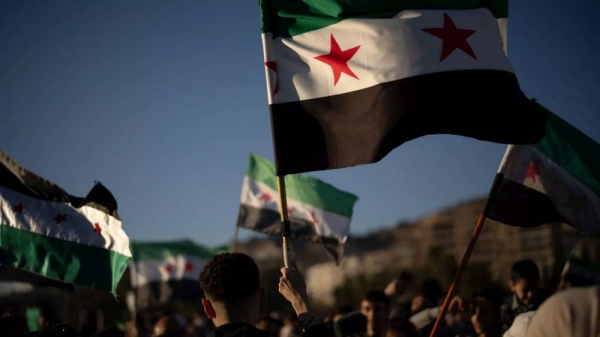 Syrians wave 'revolutionary' flags during a celebratory demonstration following the first Friday prayers since Bashar Assad's ouster, in Damascus' central square, Syria