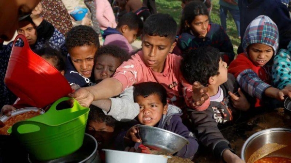 Palestinian children in Gaza gather to receive food cooked by a charity kitchen