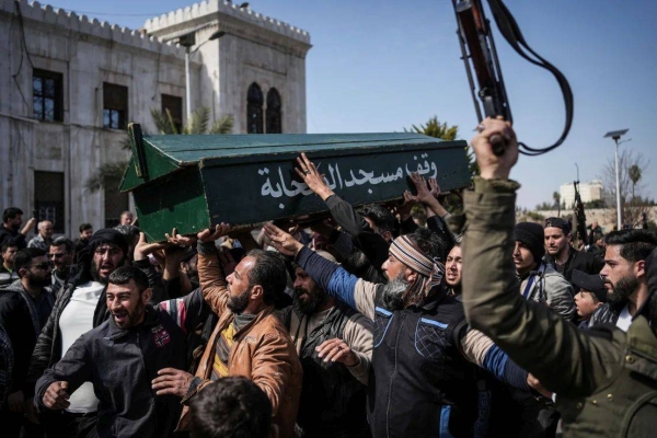 Syrian fighters and civilians carry the coffin of a member of the Syrian security forces during his funeral in Hama province, Syria on Sunday