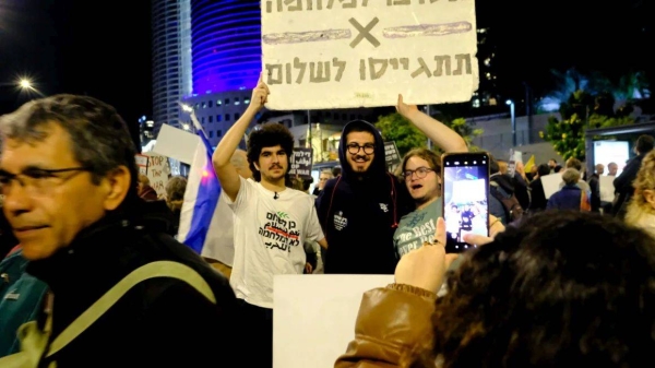 Holfing a a sign that reads, 'Refuse the war, Mobilize for peace.' refuseniks Iddo Elam (left) and Itamar Greenberg at a pro-democracy demonstration in Tel Aviv on Saturday