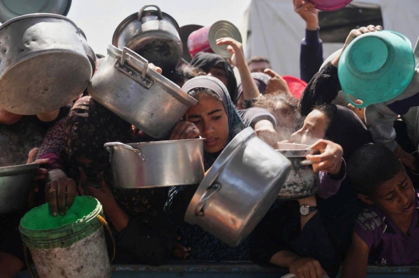 Palestinians struggle to get donated food at a community kitchen in Khan Younis, Gaza Strip on Monday