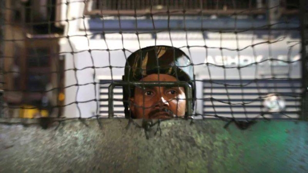 An Indian paramilitary soldier keeps watch from behind a fence in Srinagar, the summer capital of Indian-administered Kashmir