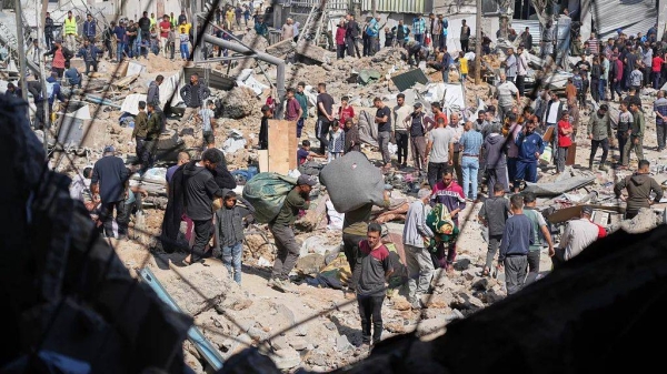 Palestinians collect belongings from a school used as a shelter by displaced residents that was hit twice by Israeli army strikes in Bureij, 7 May, 2025