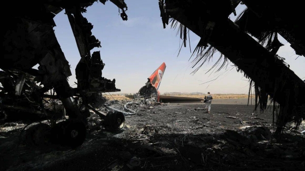 A Houthi rebel walks next to a destroyed plane at the Sanaa International Airport on Wednesday, a day after Israel's military warplanes struck Yemen's rebel-held capital Sanaa