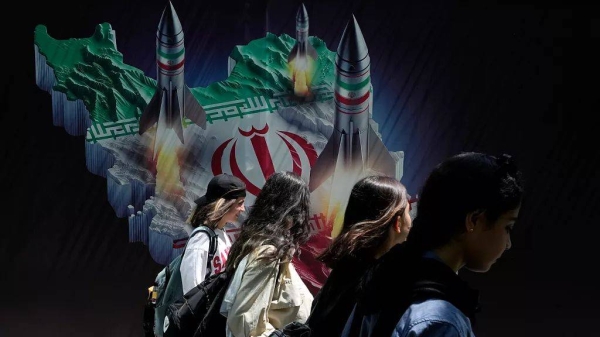 Iranian women walk past a banner showing missiles being launched from an Iranian map in Tehran, 19 April, 2024