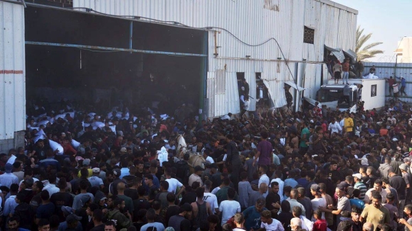 Palestinians storm a UN World Food Program warehouse and carry bags of flour in Central Gaza on Wednesday