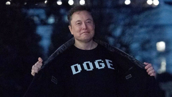 Elon Musk flashes his T-shirt that reads 'DOGE' to the media as he walks on the South Lawn of the White House, in Washington, March 9, 2025