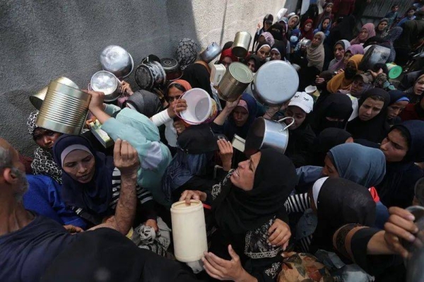 Palestinians wait in line to receive hot meals distributed by charities