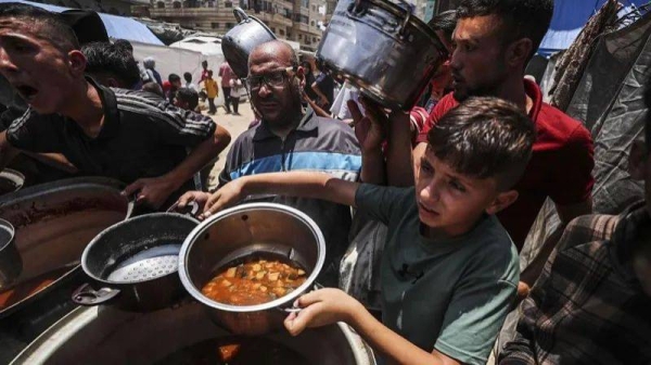Palestinians wait in line to receive hot meals distributed by charity organizations while Israel's destructive attacks continue on 7 June, 2025