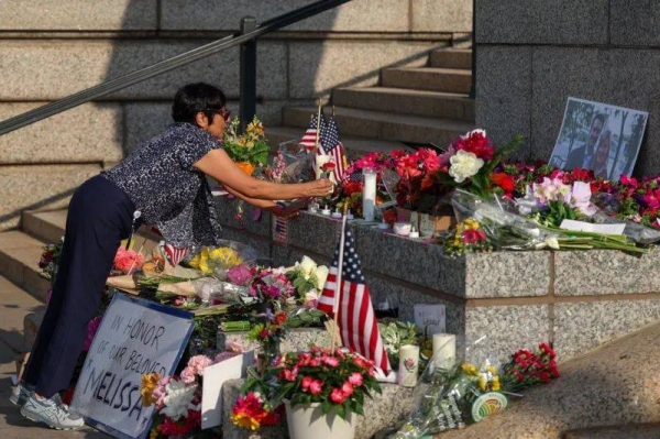 A woman lays a flower at a makeshift memorial outside the Minnesota state legislature building