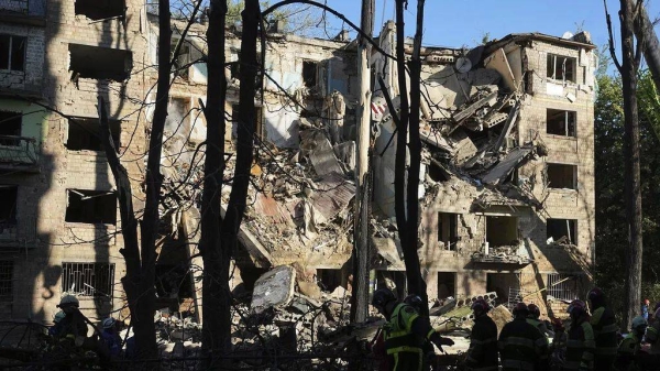 Firefighters work in a destroyed apartment building after a Russian attack in Kyiv, Ukraine, early Monday, June 23, 2025