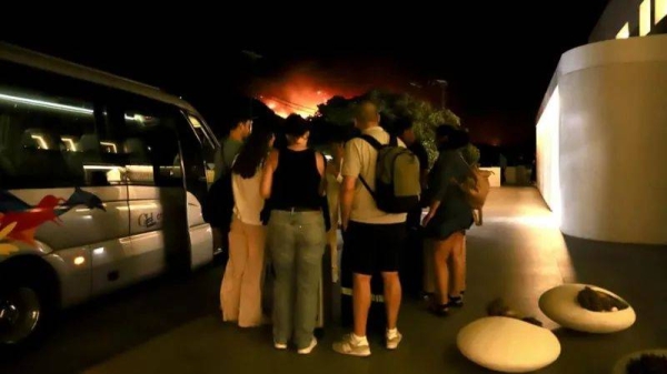 Tourists evacuate a hotel during a wildfire in Ierapetra, on Greek island of Crete