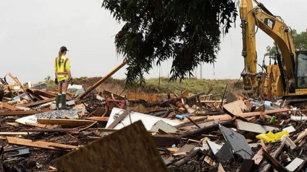Workers operate heavy machinery to clear debris after massive flooding