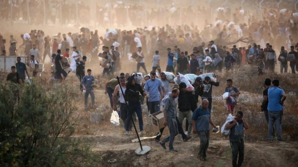 People carry relief supplies from a Gaza Humanitarian Foundation (GHF) aid distribution centre in the central Gaza Strip on June 8