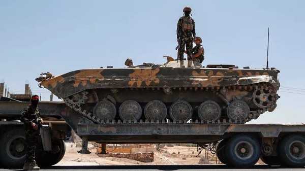Syrian government forces stand on an armoured personnel carrier carried on a truck as they withdraw from Sweida city, 15 July, 2025