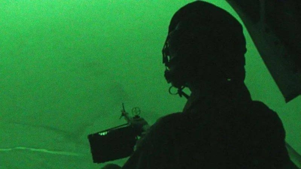 A night vision view of a British solider manning a helicopter-mounted machinegun
