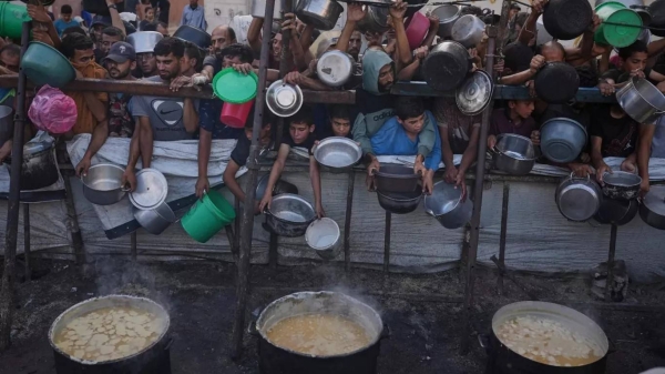 Palestinians struggle to get donated food at a community kitchen in Gaza City, 14 July, 2025