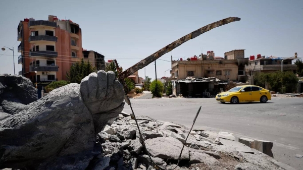 A car drives by a destroyed statue following last week's sectarian clashes in the Druze-majority town of Suwayda, 25 July 2025,