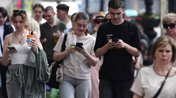 Pedestrians look at their phones while walking through St. Petersburg, Russia, on July 14, 2025