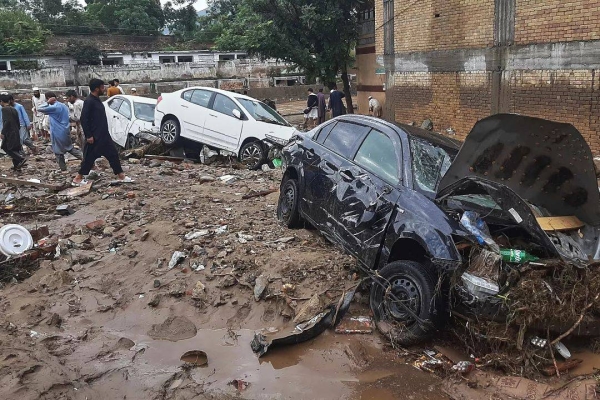Residents examine damaged cars trapped in a mud following flash flooding due to heavy rains in Mingora, the main town of Swat Valley, northwestern Pakistan, 15 August 2025