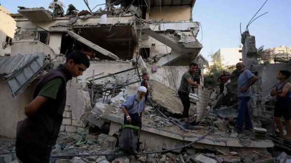 Palestinians inspect the site of an overnight Israeli strike on a house, in Gaza City